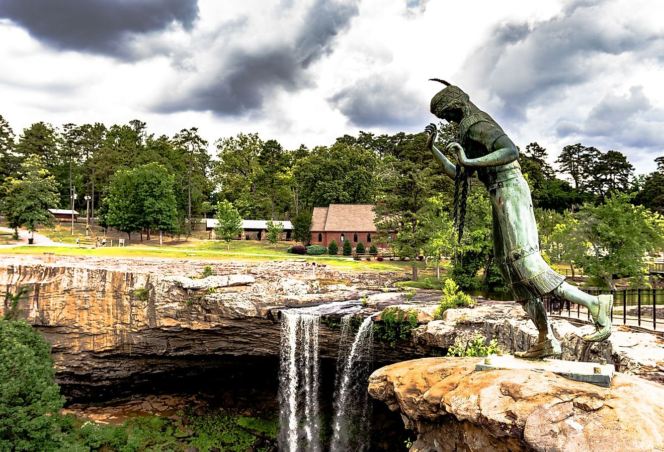  The bronze statue of a young Cherokee woman named Noccalula, who legend says plunged to her death at this point with Noccalula Falls in the background. Image credit JNix via Shutterstock.